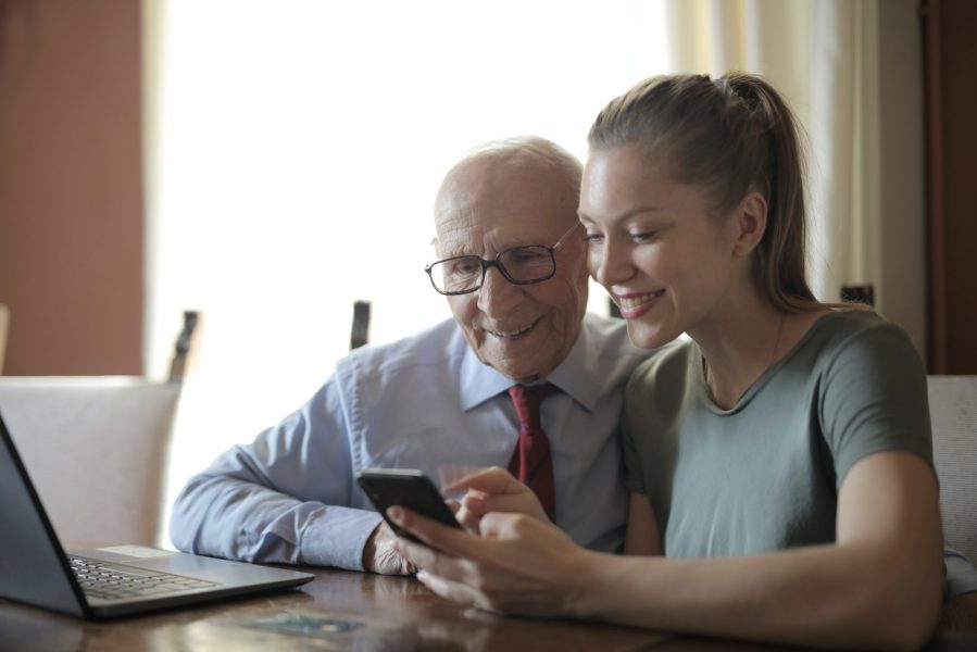 Una giovane donna illustra le funzioni di uno smartphone a un uomo anziano.